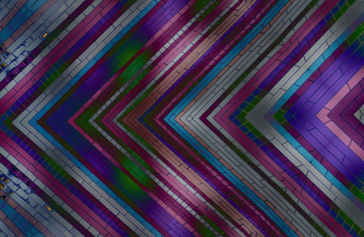 a tiled wall solarized into metallic pink, blue, white, purple, and beige colours with a green gloe in some parts, mirrored halfway down