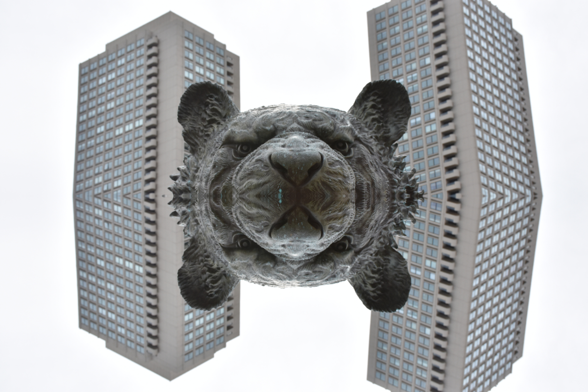 half the face of a statue of a bear with a white sky and two high rise buildings behind it, mirrored halfway down.