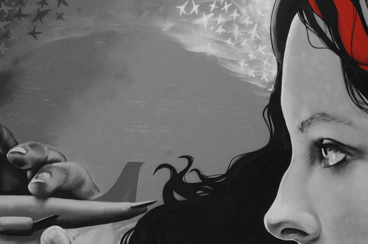 a mural of the top half of a woman's face in profile, with long flowing hair, holding a tiny airplane in her fingers. the image is in black and white except for a headband the woman is wearing, which is bright red.