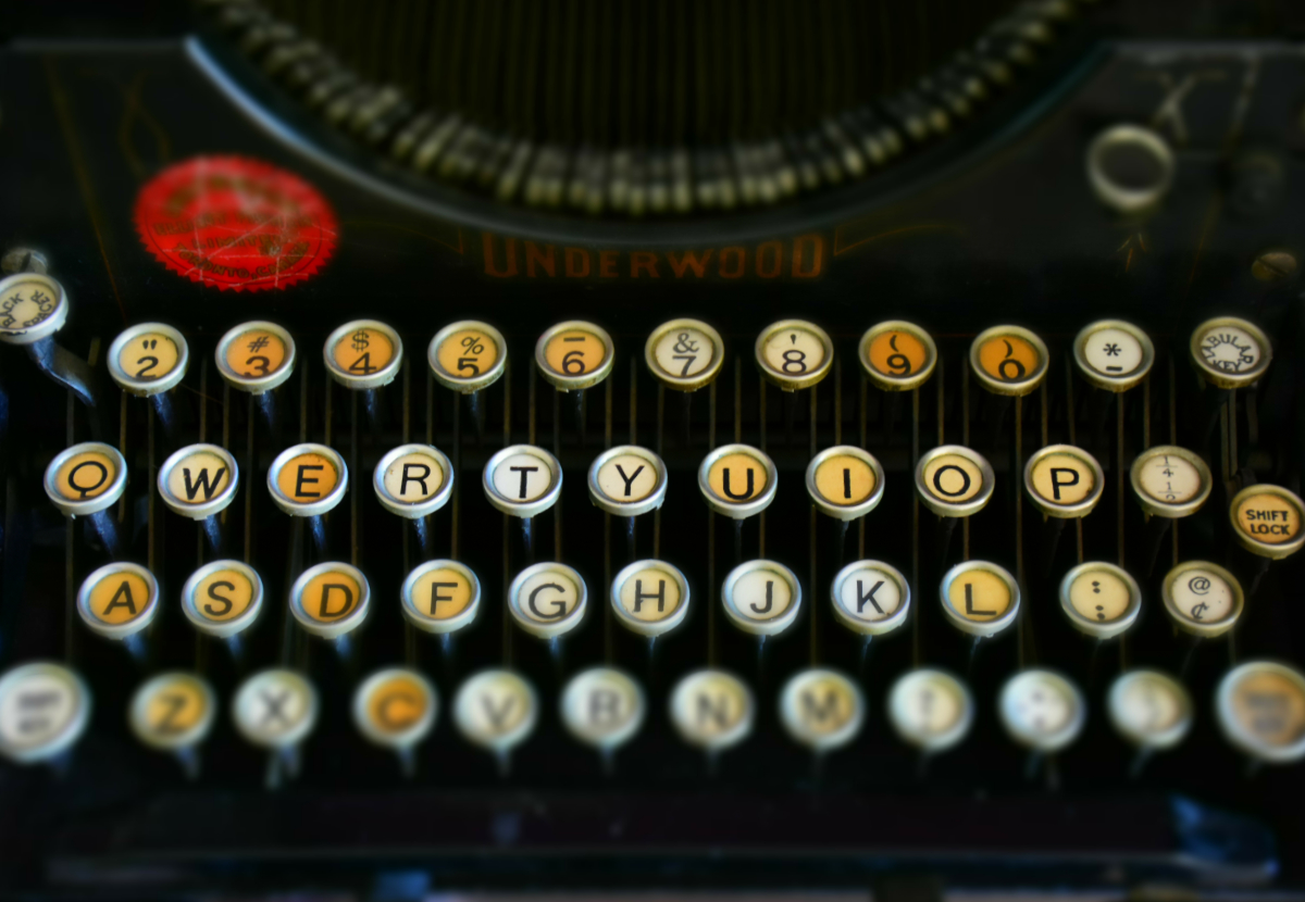 a tilt shift closeup of an early 20th century typewriter with only the Q-P and A-L rows in focus