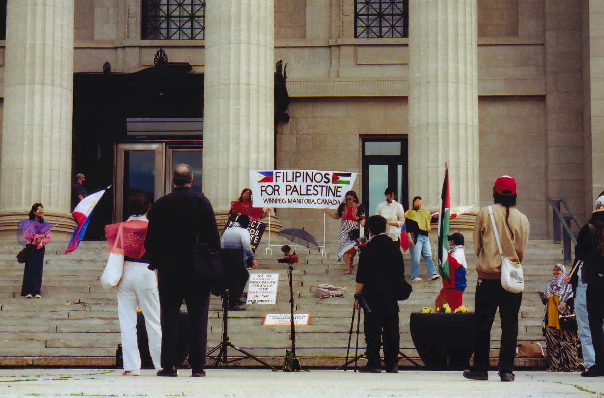 about a dozen people standing on or around the steps of the Manitoba Legislature. Two are holding a sign saying 'Filipinos for Palestine, Winnipeg, Manitoba, Canada' with both the Filipino and Palestinian flags. One person on the left is holding a Filipinio flag and one person on the right is holding a Palestinian flag. There's another sign resting on the steps saying 'NO to Canada's Indo-Pacific Strategy! Stop WAR CRIMES in the Philippines'