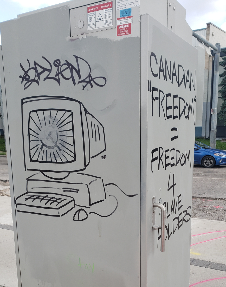 a large grey power box with an old CRT monitor graffitied on one side with a hammer and sickle on the screen, and on the adjacent side a message saying 'CANADIAN 'FREEDOM' = FREEDOM 4 SLAVE HOLDERS'