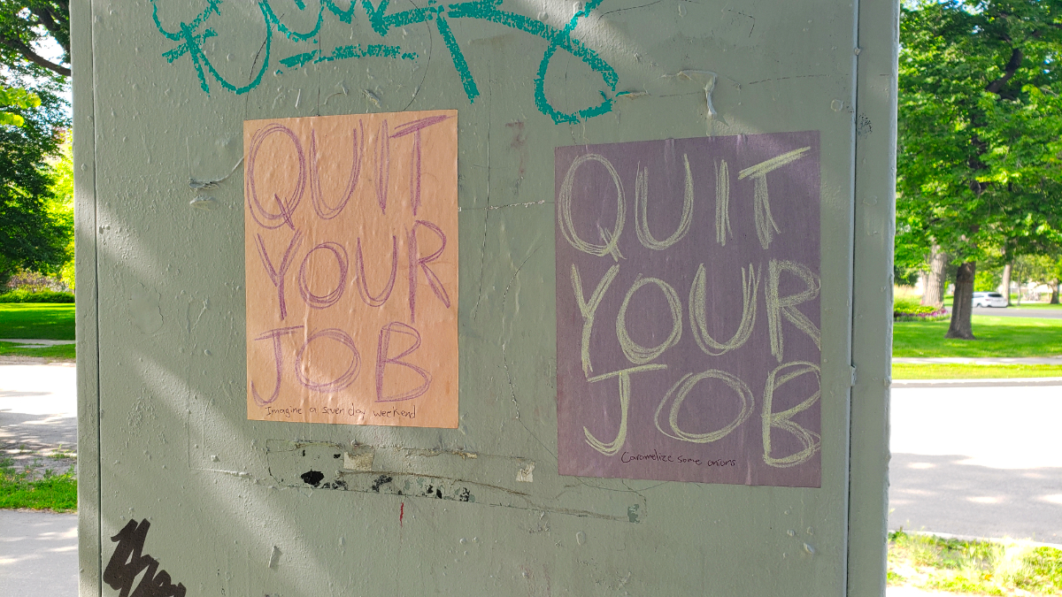 A grey hydro box of some kind with two QUIT YOUR JOB posters. One is beige with purple writing and ends with 'Imagine a seven day weekend' and the other is purple with silver writing with 'Caramelize some onions'.