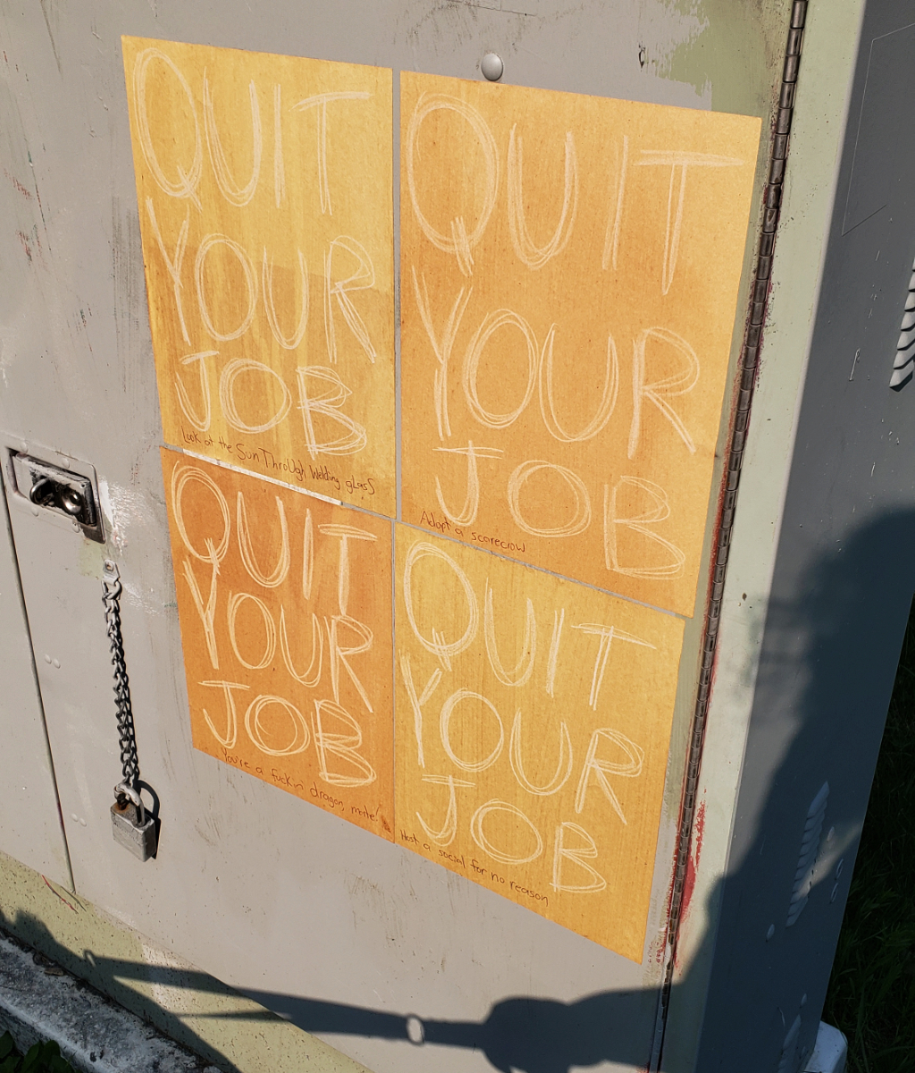 A grey metal surface with four QUIT YOUR JOB posters, 2x2, with the messages: 'Look at the sun through welding glass', 'Adopt a scarecrow', 'You're a fucking dragon, mate!', 'Host a social for no reason'. You can see my shadow on the side and the fact that I'm holding a leash.