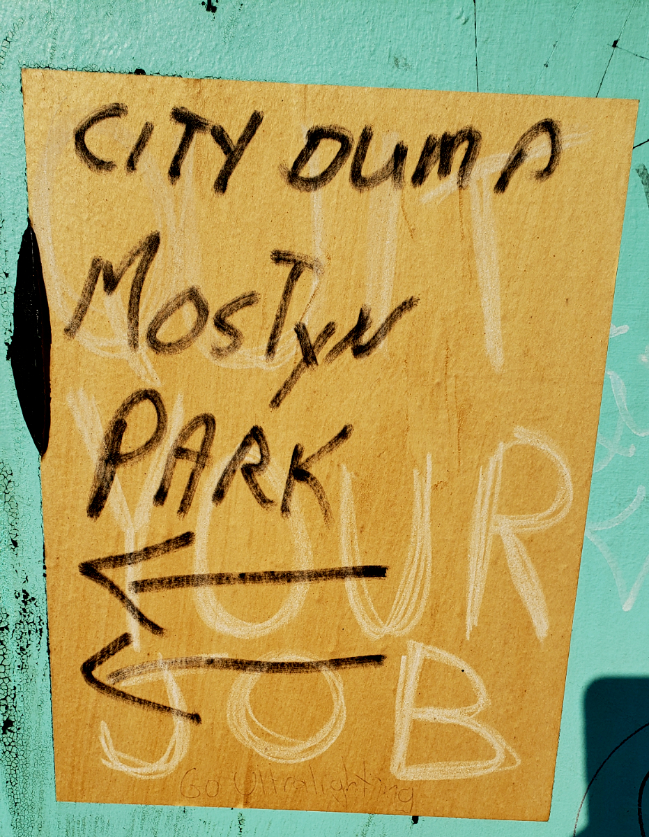 'City Dump Mostyn Park' with arrows written overtop of a QUIT YOUR JOB poster with 'Go Ultralightning' in pen