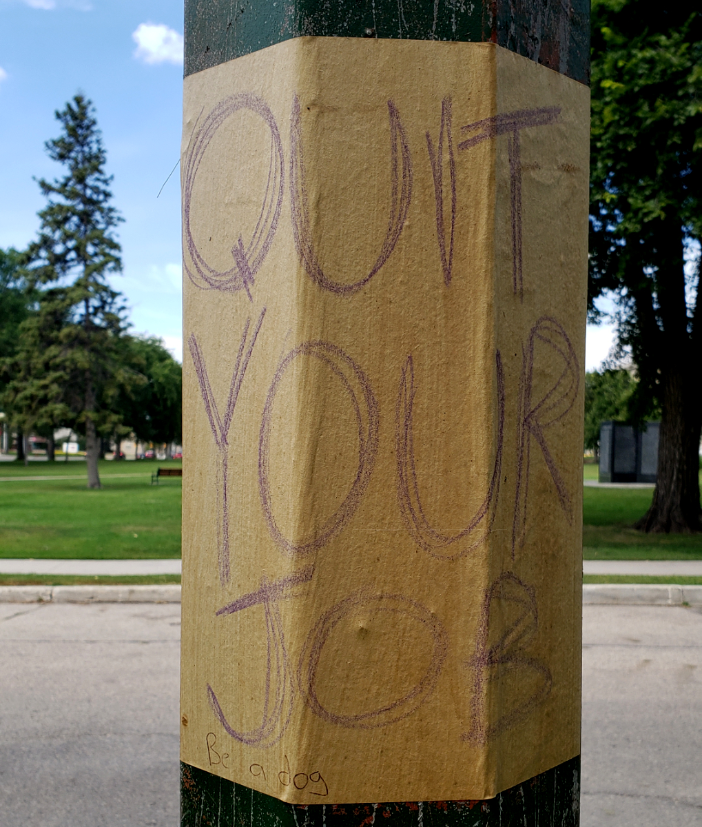 QUIT YOUR JOB sign on a lamppost with 'Be a dog' in pen