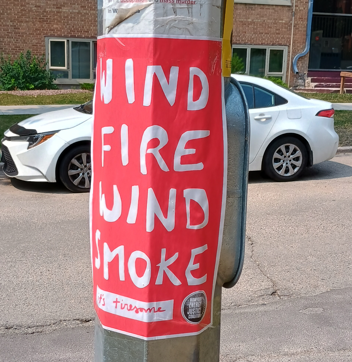 a red poster with text cut out saying 'wind fire wind smoke' and a white block at the bottom with red cursive writing saying 'it's tiresome'