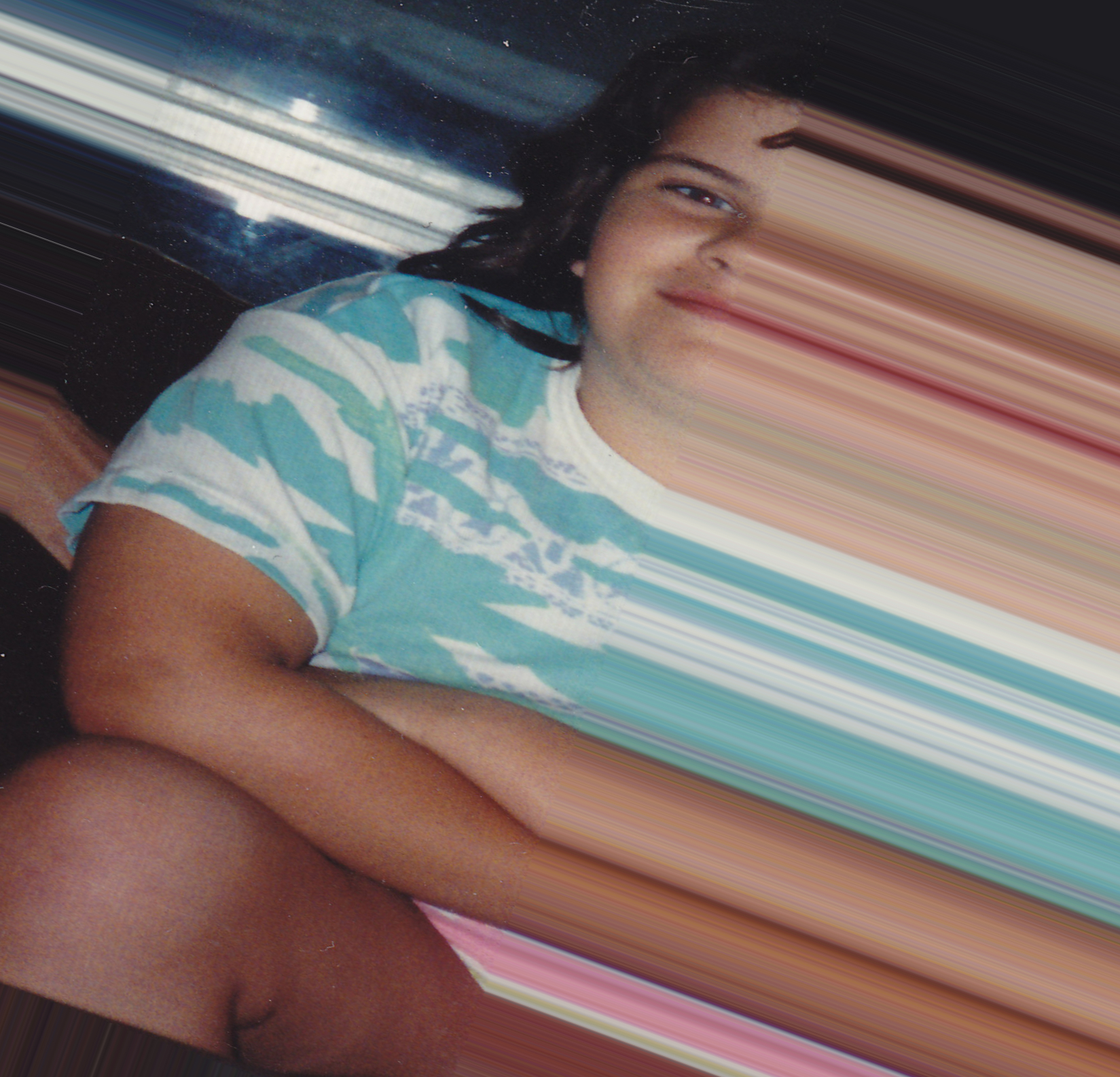 An photograph from the early 90s of a fat kid sitting with their hands crossed leaning on their lap, half-smiling with a double chin and bad haircut, with the image rotated slightly clockwise and the kid cropped halfway with the colours stretched towards the bottom right corner to make it look like a blury smudge of a face and body